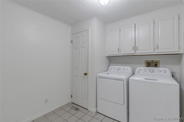 clothes washing area with cabinets, a textured ceiling, light tile patterned flooring, separate washer and dryer, and ornamental molding