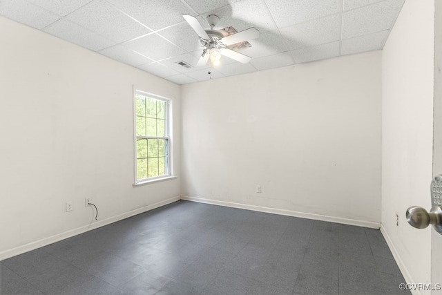 tiled empty room with ceiling fan and a paneled ceiling