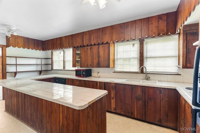 kitchen with tile counters, light colored carpet, sink, and ceiling fan