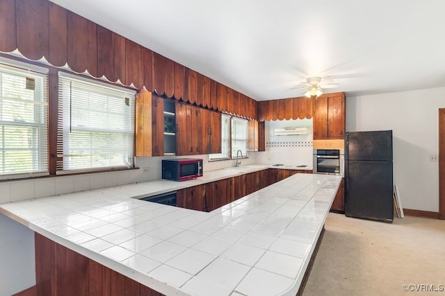 kitchen featuring tile counters, kitchen peninsula, ceiling fan, appliances with stainless steel finishes, and sink