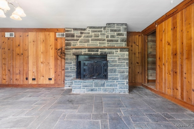 unfurnished living room featuring a fireplace and wooden walls