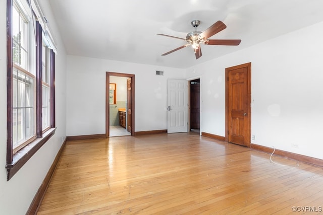 unfurnished bedroom featuring light hardwood / wood-style floors, multiple windows, ensuite bathroom, and ceiling fan