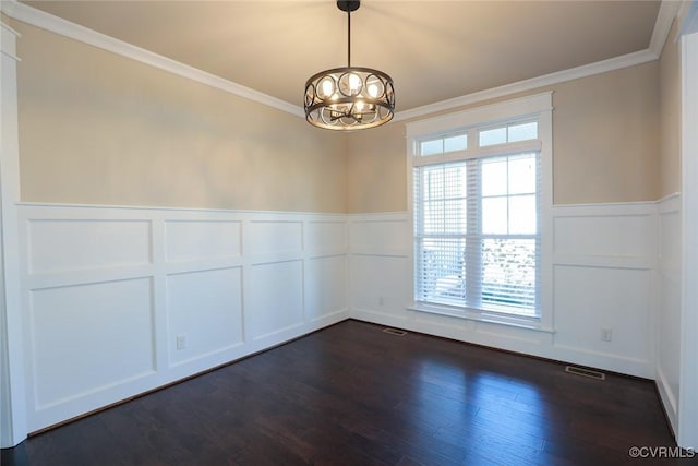 spare room featuring dark hardwood / wood-style flooring, ornamental molding, and an inviting chandelier