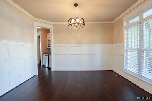 unfurnished room featuring plenty of natural light, dark hardwood / wood-style floors, ornamental molding, and a chandelier