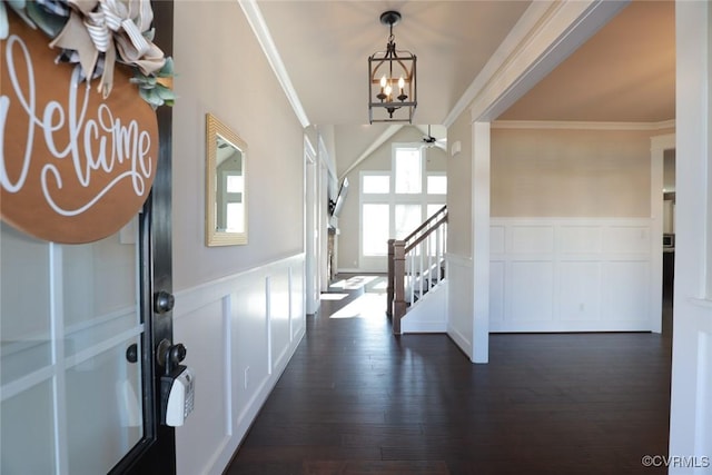 entryway with crown molding, dark wood-type flooring, and ceiling fan with notable chandelier