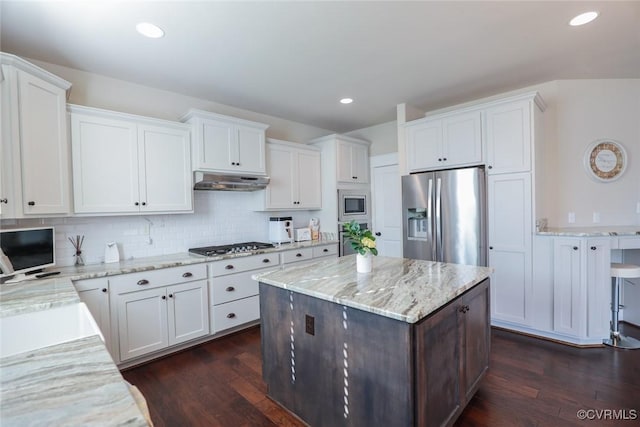 kitchen with appliances with stainless steel finishes, tasteful backsplash, white cabinetry, a center island, and dark hardwood / wood-style floors