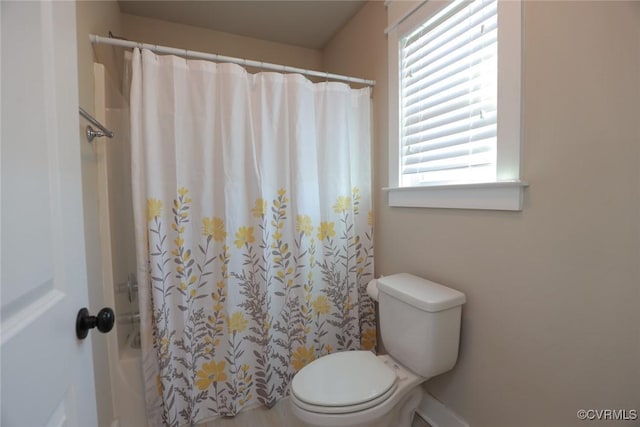 bathroom with curtained shower, a wealth of natural light, and toilet