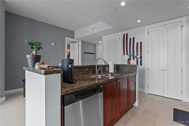 kitchen featuring light tile patterned flooring, dark stone counters, dishwasher, a kitchen island, and sink