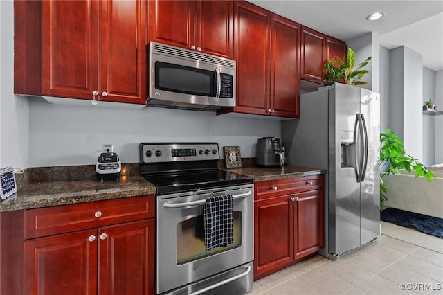 kitchen featuring appliances with stainless steel finishes, dark stone counters, and light tile patterned floors