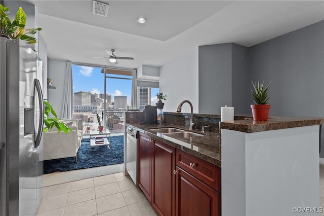 kitchen with dark stone counters, light tile patterned flooring, ceiling fan, sink, and appliances with stainless steel finishes