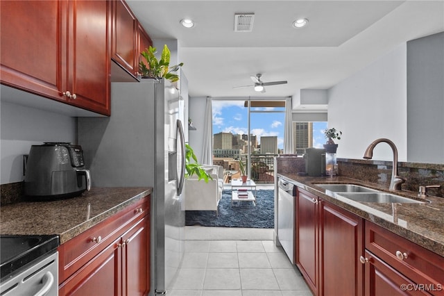 kitchen featuring ceiling fan, sink, dark stone countertops, stove, and light tile patterned floors