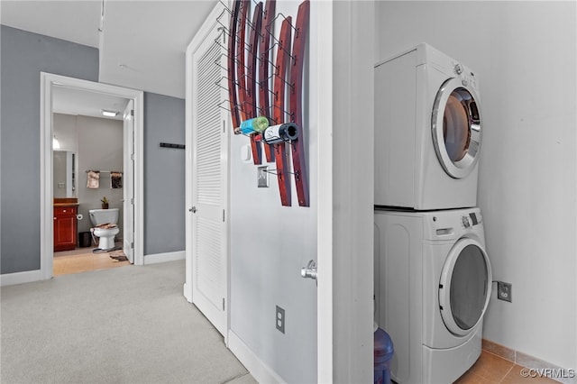 laundry room featuring stacked washer and dryer and light tile patterned floors