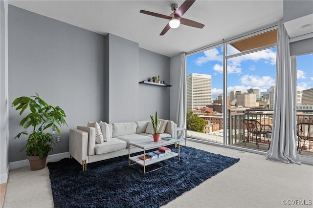 carpeted living area featuring baseboards, a view of city, ceiling fan, and expansive windows