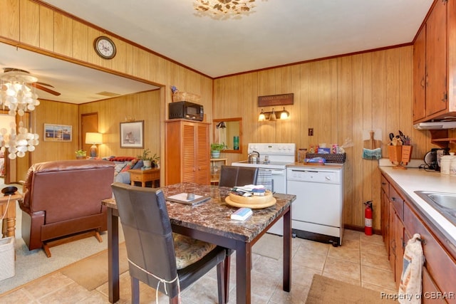 interior space with wood walls, light tile patterned floors, ornamental molding, white dishwasher, and ceiling fan