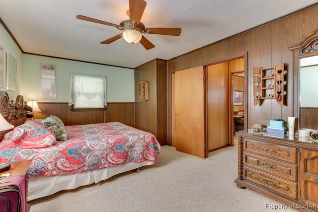 carpeted bedroom featuring ceiling fan and wooden walls