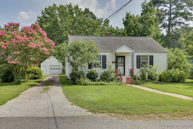 view of front of home featuring a front lawn, a garage, and an outbuilding