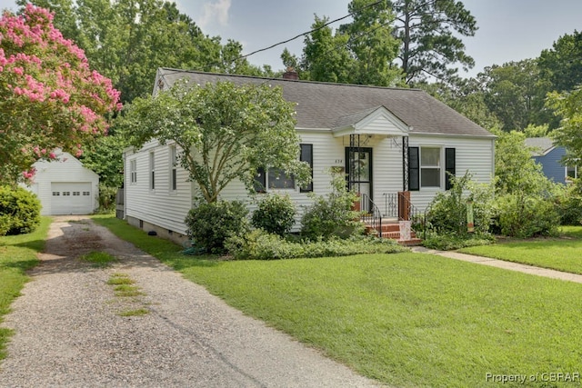 view of front of house with a garage, a front lawn, and an outbuilding