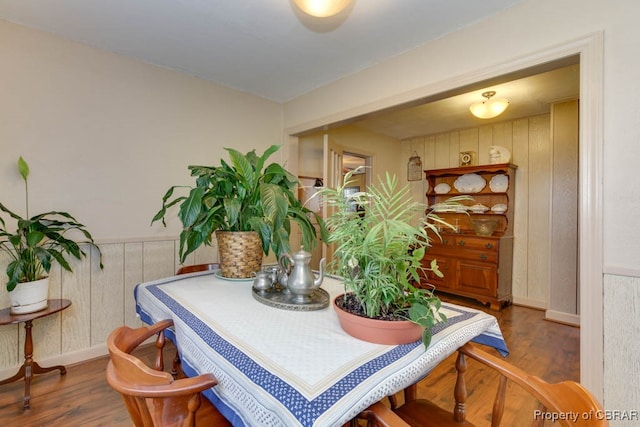 dining area featuring hardwood / wood-style flooring and wooden walls