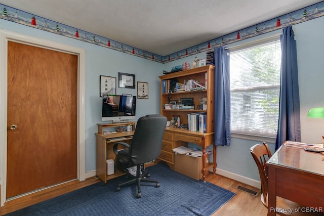 home office with light hardwood / wood-style flooring