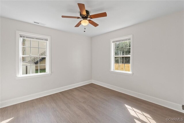 empty room with ceiling fan, hardwood / wood-style flooring, and a healthy amount of sunlight