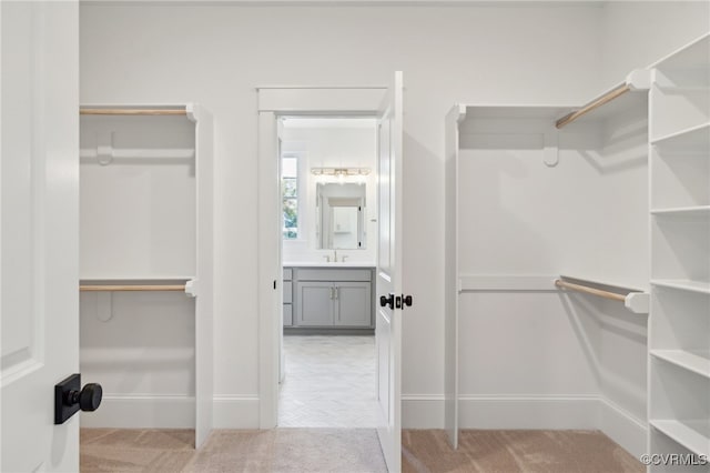 walk in closet featuring sink and light carpet