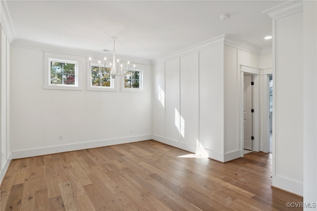 empty room featuring crown molding, light hardwood / wood-style flooring, and an inviting chandelier