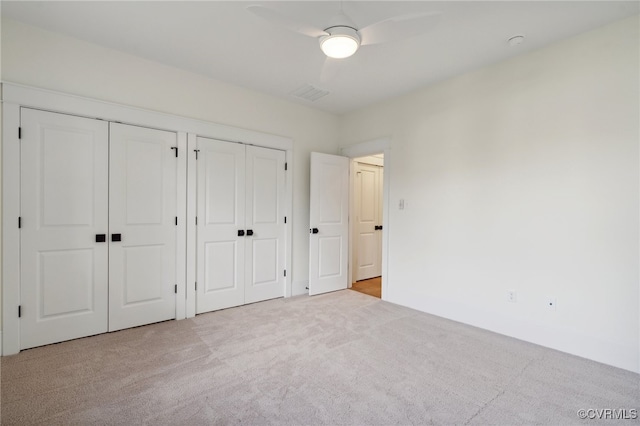 unfurnished bedroom with light carpet, two closets, and ceiling fan