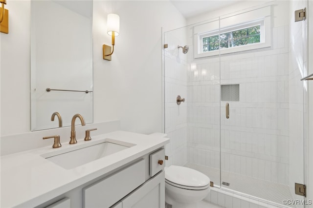 bathroom featuring toilet, vanity, and a shower with door