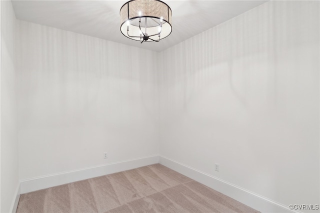 carpeted spare room with an inviting chandelier