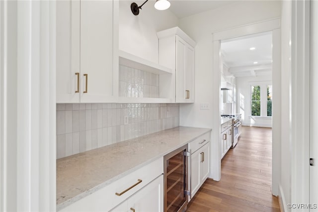 bar featuring light hardwood / wood-style flooring, wine cooler, white cabinets, and light stone counters