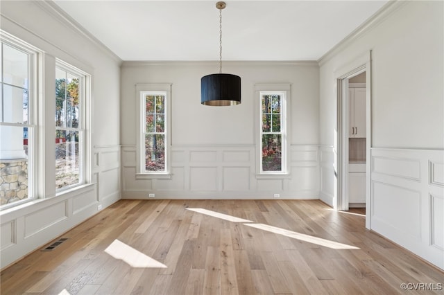 unfurnished dining area with a wealth of natural light, crown molding, and light wood-type flooring