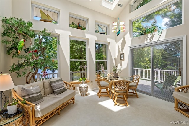 sunroom / solarium featuring visible vents, plenty of natural light, and vaulted ceiling with skylight