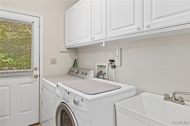 washroom with sink, washing machine and clothes dryer, and cabinets