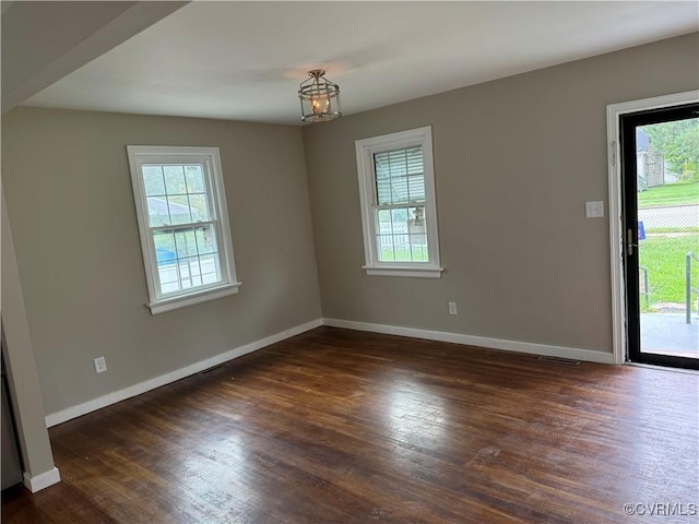 empty room with dark wood finished floors, baseboards, and a wealth of natural light