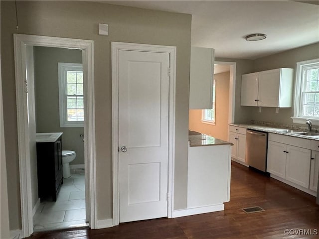 kitchen with dishwasher, dark wood finished floors, white cabinetry, and a sink