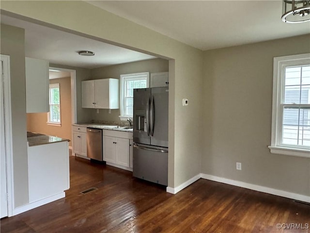 kitchen with a healthy amount of sunlight, white cabinetry, stainless steel appliances, and baseboards