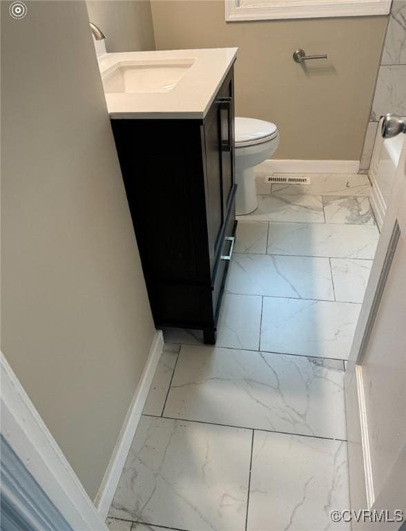 bathroom featuring marble finish floor, toilet, vanity, and baseboards