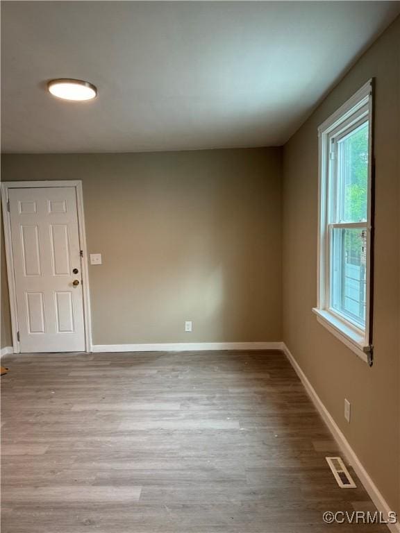 empty room with visible vents, baseboards, and wood finished floors