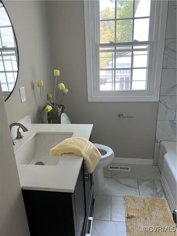 full bath with visible vents, marble finish floor, baseboards, a bathtub, and vanity