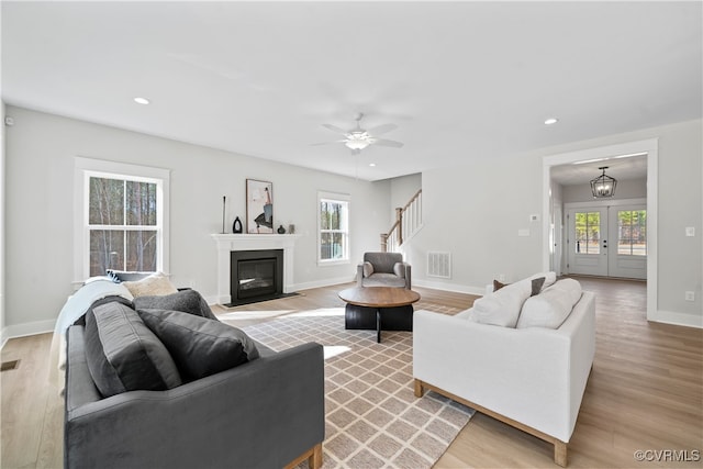 living room featuring ceiling fan, plenty of natural light, and light hardwood / wood-style floors