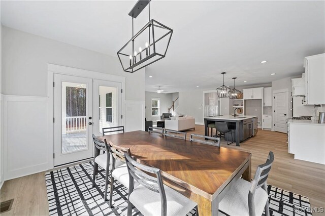 dining area featuring sink, ceiling fan with notable chandelier, plenty of natural light, and light hardwood / wood-style floors