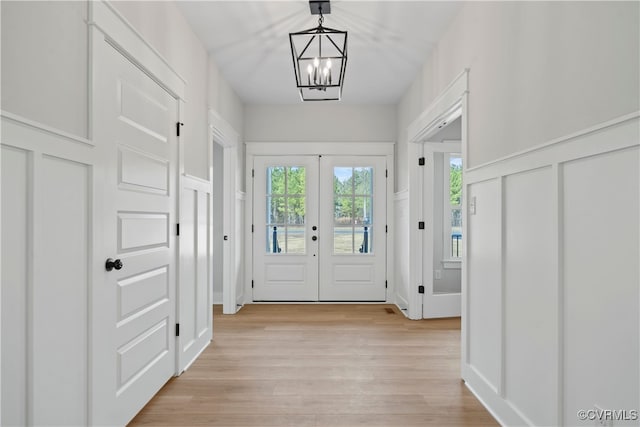 doorway with a notable chandelier, french doors, and light hardwood / wood-style floors