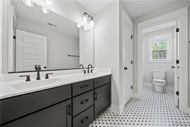 bathroom with toilet, dual bowl vanity, and tile patterned floors