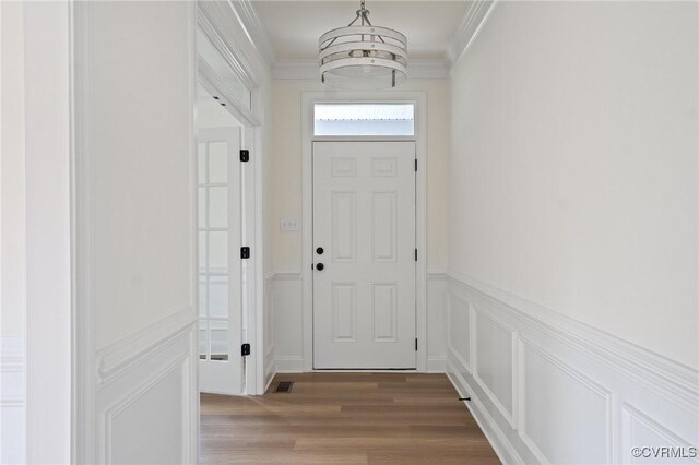 entryway with wood-type flooring and ornamental molding