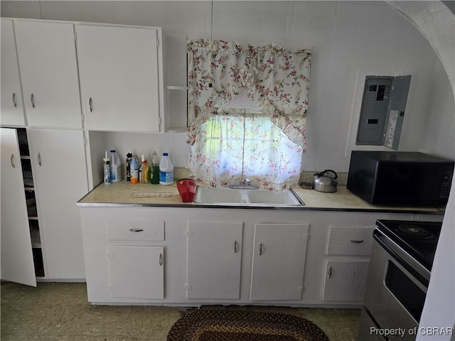 kitchen featuring light tile patterned floors, range with electric cooktop, sink, and white cabinetry