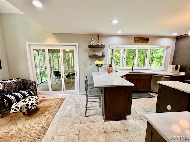 kitchen featuring sink, stainless steel dishwasher, a kitchen bar, and light tile patterned floors