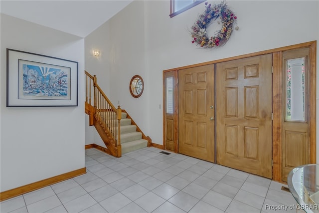 foyer entrance with light tile patterned flooring and a high ceiling