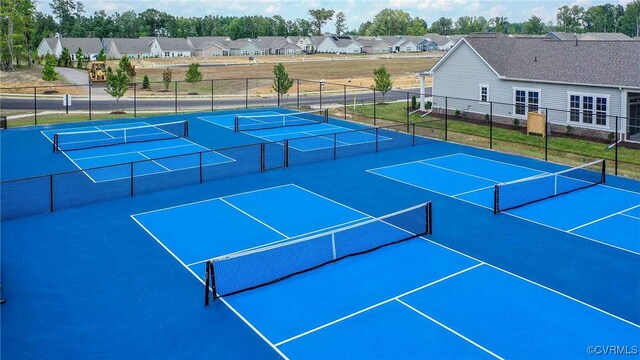 view of tennis court with a residential view and fence