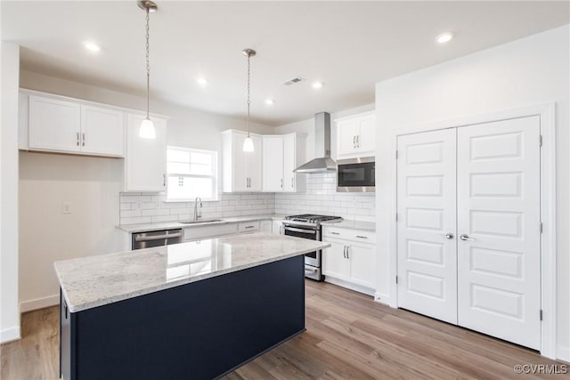 kitchen featuring a center island, stainless steel appliances, backsplash, a sink, and wall chimney exhaust hood