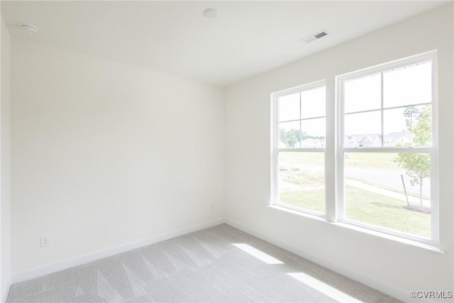 unfurnished room featuring visible vents, light carpet, and baseboards